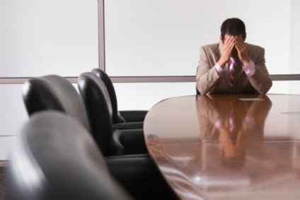 Businessman sitting at conference table, with head in hands
