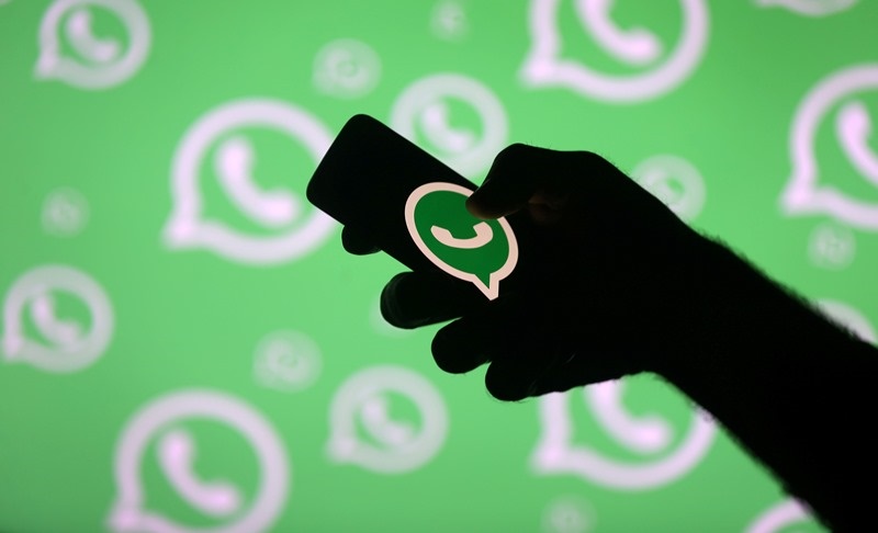 FILE PHOTO: A man poses with a smartphone in front of displayed Whatsapp logo in this illustration September 14, 2017. REUTERS/Dado Ruvic/File Photo