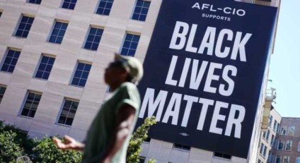 A man is seen in front of a large ‘Black Lives Matter’ banner on the side of the AFL-CIO building near the White House in Washington, DC on June 12, 2020. (Photo by MANDEL NGAN / AFP)