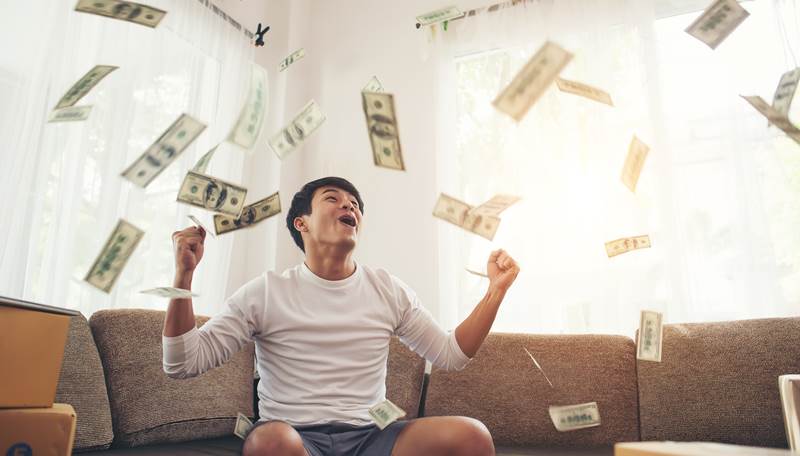 Happy man with cash dollars flying in home office, Rich from business online concept