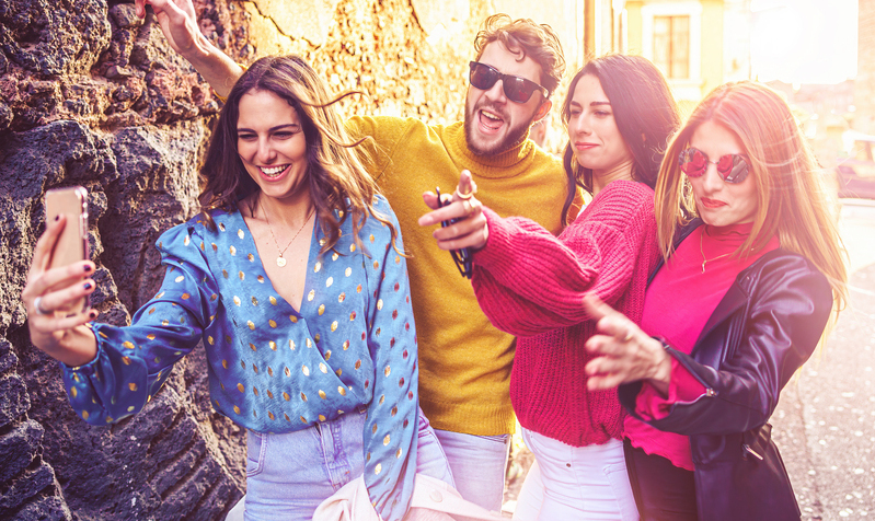 Group of best friends funny young people taking a selfie in the old city center. Young people having fun using smartphones