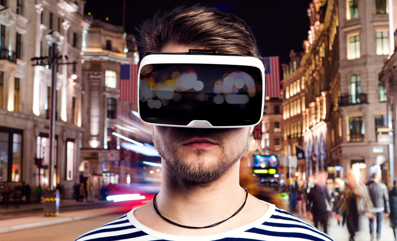 Man wearing virtual reality goggles against illuminated night city