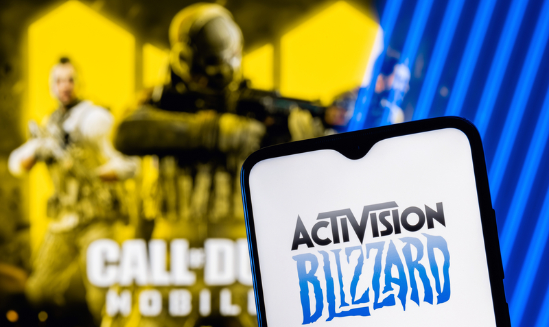 Kazan, Russia – August 7, 2021: Activision Blizzard, Inc. is an American video game holding company. Activision Blizzard logo on smartphone screen. A frame from the Call of Duty on the background.