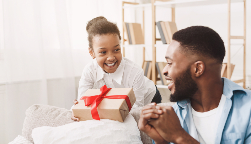 Birthday gift. Afro girl giving present to father, making handmade surprise , free space