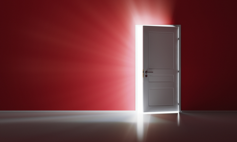 Rays of light through the open white door on red wall