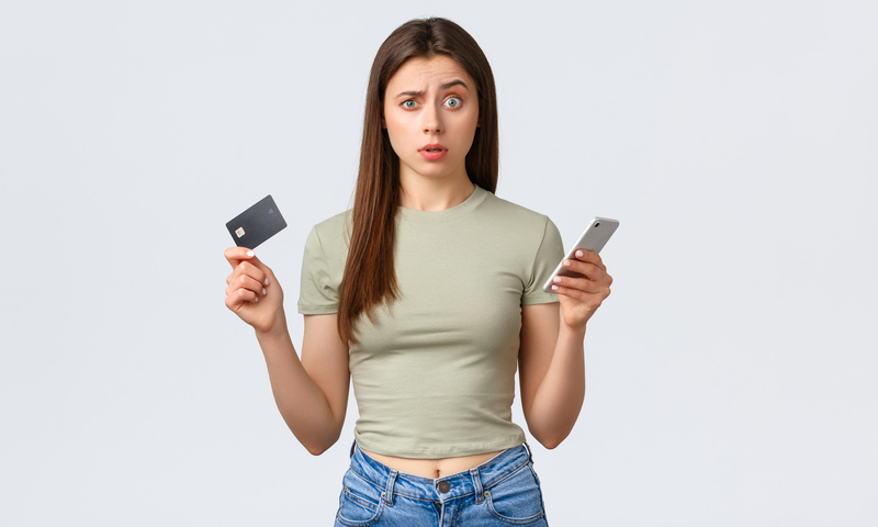 Online shopping, home lifestyle and people concept. Confused and puzzled pretty woman with credit card and mobile phone raise one eyebrow and looking camera uncertain, white background.