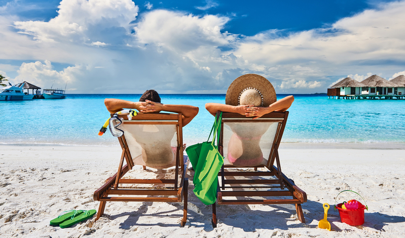 Couple in sun beds on a tropical beach at Maldives