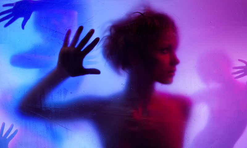 Silhouette of young woman listening standing behind curtain