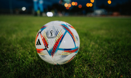QATAR, DOHA, 18 JULY, 2022: Official Adidas Fifa World Cup Football Ball Al Rihla. World Championship in Qatar 2022. Soccer Match Ball on green grass in night at Stadium. FIFA 22, black edit space.