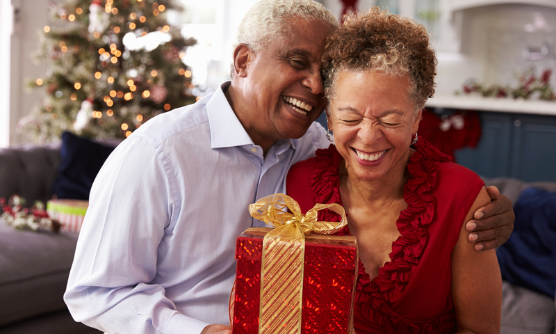 Senior Couple Exchanging Christmas Gifts At Home