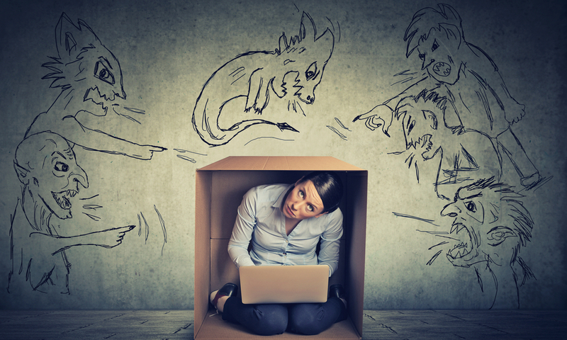 Bad evil men pointing at stressed woman. Desperate scared businesswoman hiding in a box working on laptop grey office wall background. Negative human emotions face expression feelings life perception