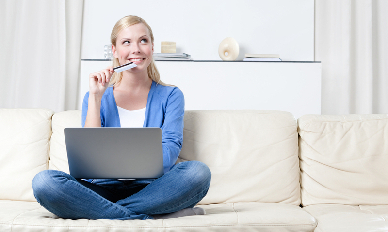 Young girl thinks about purchasing through the internet sitting on the sofa