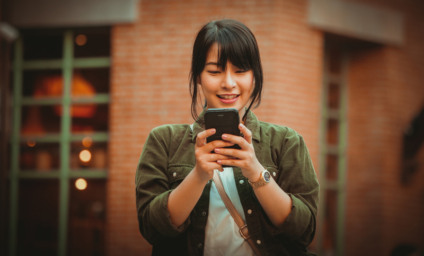 Asian woman using smartphone with happy mood smile face in shopping mall