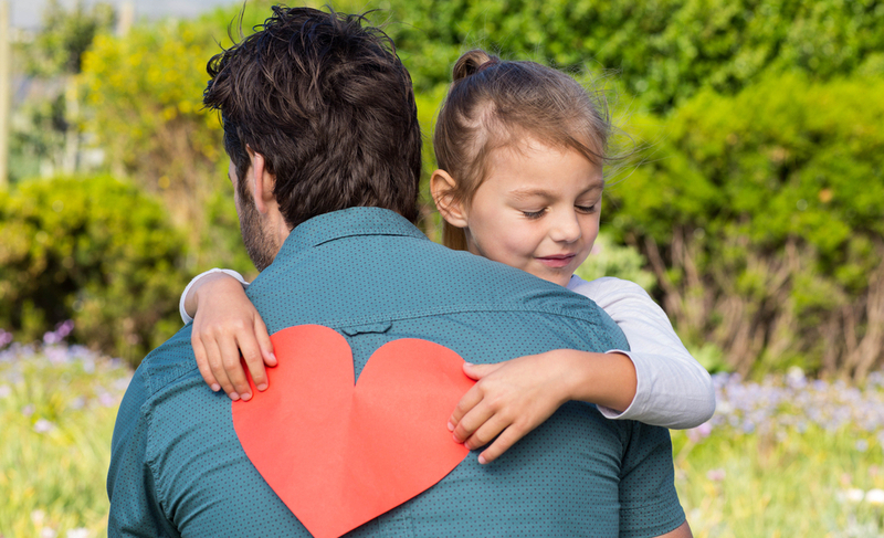 Daughter giving dad a heart card in the countryside