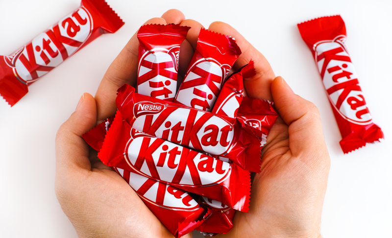 Tambov, Russian Federation – January 30, 2021 Woman palms full of KitKat candies by Nestle. White background.