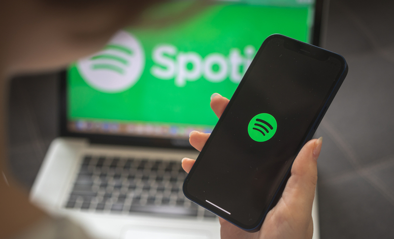 Kharkov, Ukraine – August 25, 2021: Woman using Spotify application and holding smartphone, close-up