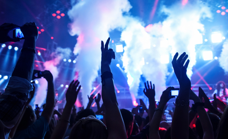 Picture of rock concert, music festival, New Year eve celebration, party in nightclub, dance floor, disco club, many people standing with raised hands up and clapping, happiness and night life concept