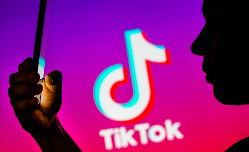 April 6, 2023, Brazil. In this photo illustration, a woman’s silhouette holds a smartphone with the TikTok logo in the background