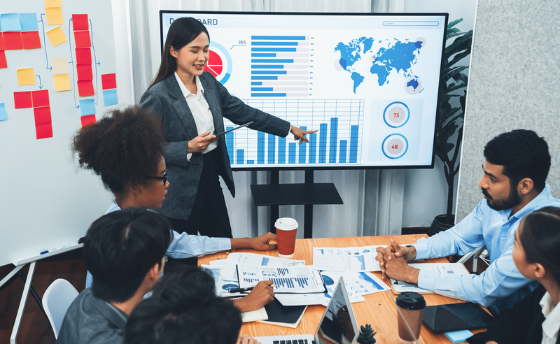 Young asian businesswoman presenting data analysis dashboard on TV screen in modern meeting. Business presentation with group of business people in conference room. Concord