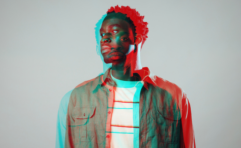 Waist-up studio portrait of a young male model. The image has an RBG split effect.