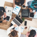 Top view of businessman executive in group meeting with other businessmen and businesswomen in modern office with laptop computer, coffee and document on table. People corporate business team concept.