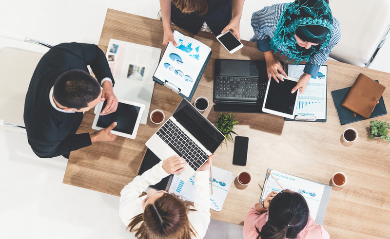 Top view of businessman executive in group meeting with other businessmen and businesswomen in modern office with laptop computer, coffee and document on table. People corporate business team concept.