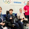 Jogadoras de bocha do Time Coreia, Sunhee Kang e So Yeong Jeong, o jogador de rúgbi em cadeira de rodas do Time Dinamarca, Kurt Busk, o presidente do Comitê Paralímpico Internacional, Andrew Parsons, e o jogador de basquete em cadeira de rodas do Time França, Jordan Luce, posam juntos no espaço pop-up Samsung Experience na Vila Olímpica e Paralímpica