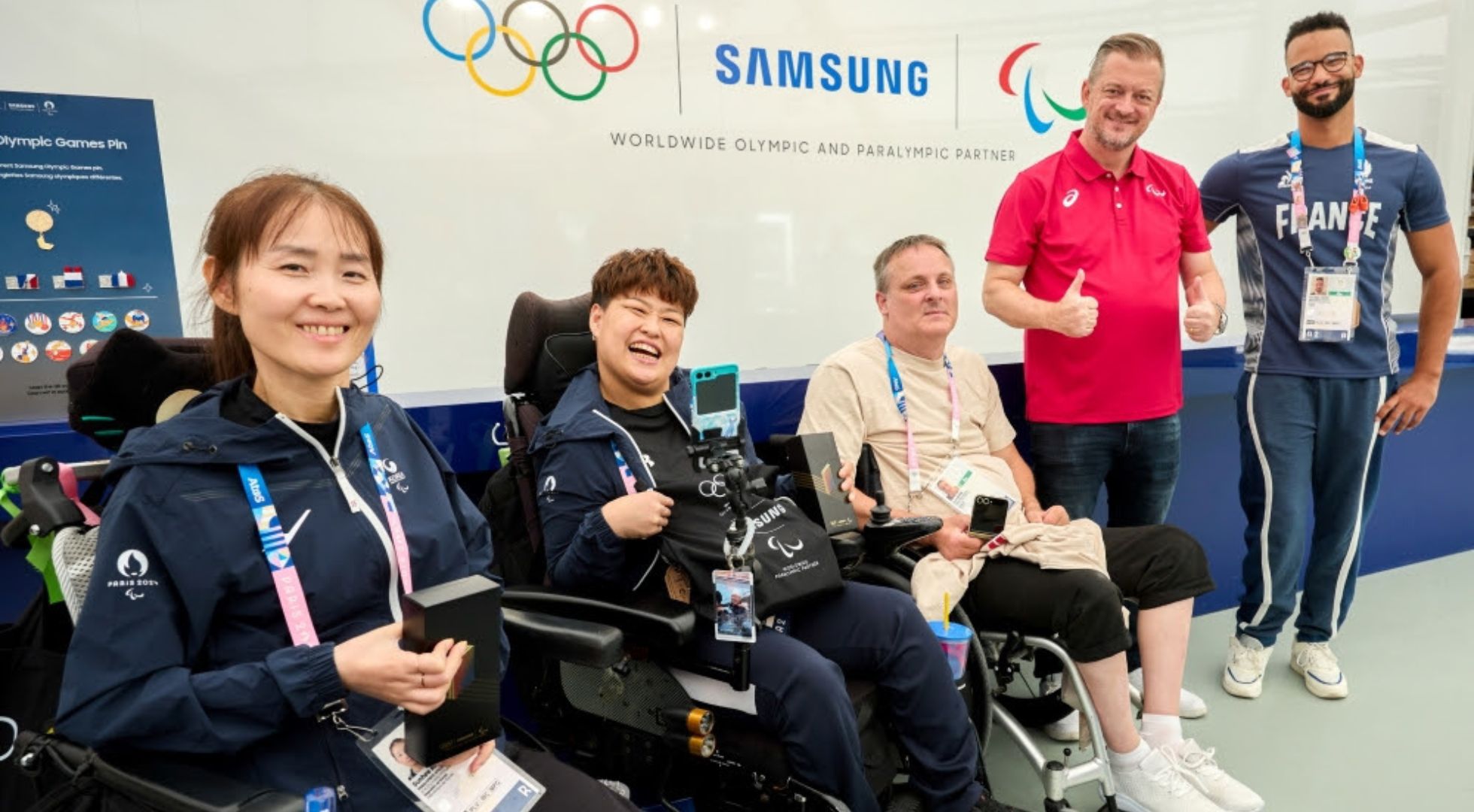 Jogadoras de bocha do Time Coreia, Sunhee Kang e So Yeong Jeong, o jogador de rúgbi em cadeira de rodas do Time Dinamarca, Kurt Busk, o presidente do Comitê Paralímpico Internacional, Andrew Parsons, e o jogador de basquete em cadeira de rodas do Time França, Jordan Luce, posam juntos no espaço pop-up Samsung Experience na Vila Olímpica e Paralímpica