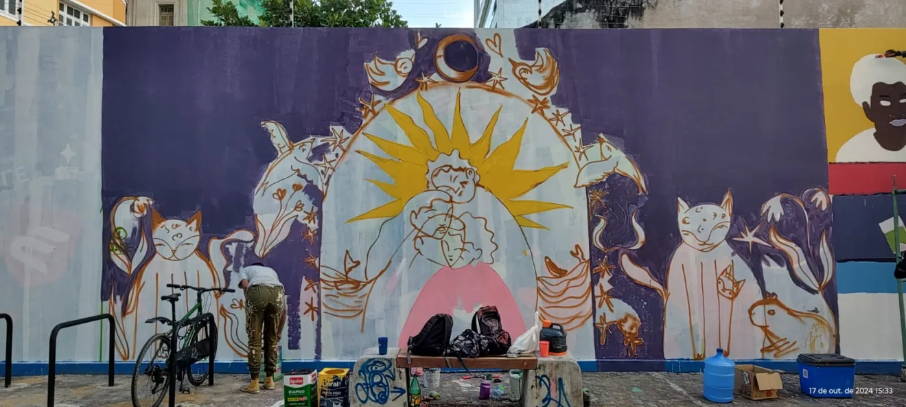 Mural artístico da r.u.a dos amores, em Recife, possui pinturas de mulheres abraçadas, gatos, pássaros, capivara e plantas. As cores roxo e amarelo são predominantes.