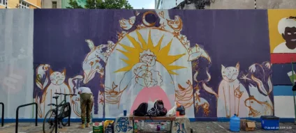 Mural artístico da r.u.a dos amores, em Recife, possui pinturas de mulheres abraçadas, gatos, pássaros, capivara e plantas. As cores roxo e amarelo são predominantes.