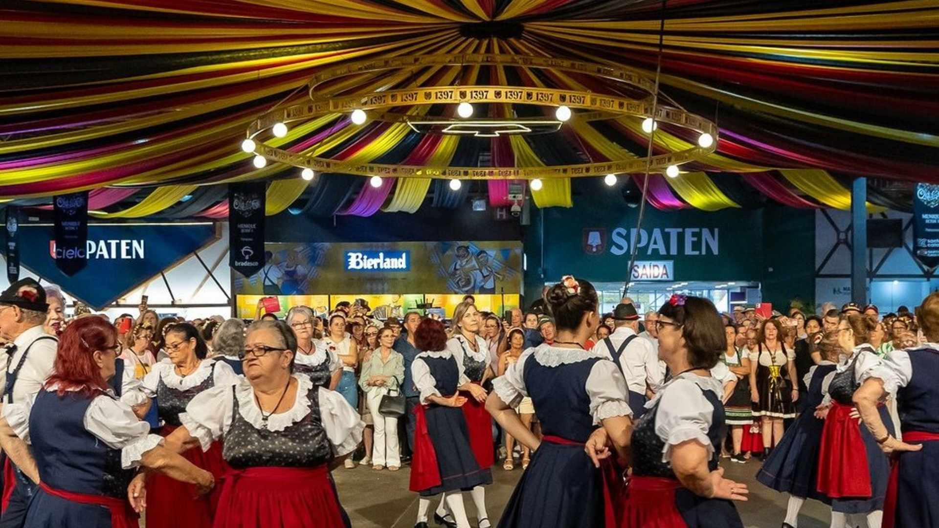 Pessoas dançando em trajes típicos alemães na Oktoberfest Blumenau 2024