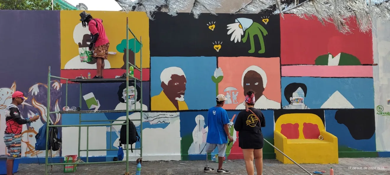 Mural artístico na r.u.a das flores traz retratos de pessoas da cidade, com fundos coloridos em azul, amarelo, rosa e outras cores vibrantes