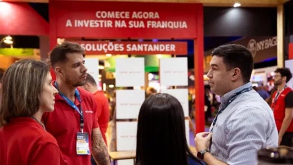 Pessoas conversam em frente ao espaço "Soluções Santander" na ABF Franchising