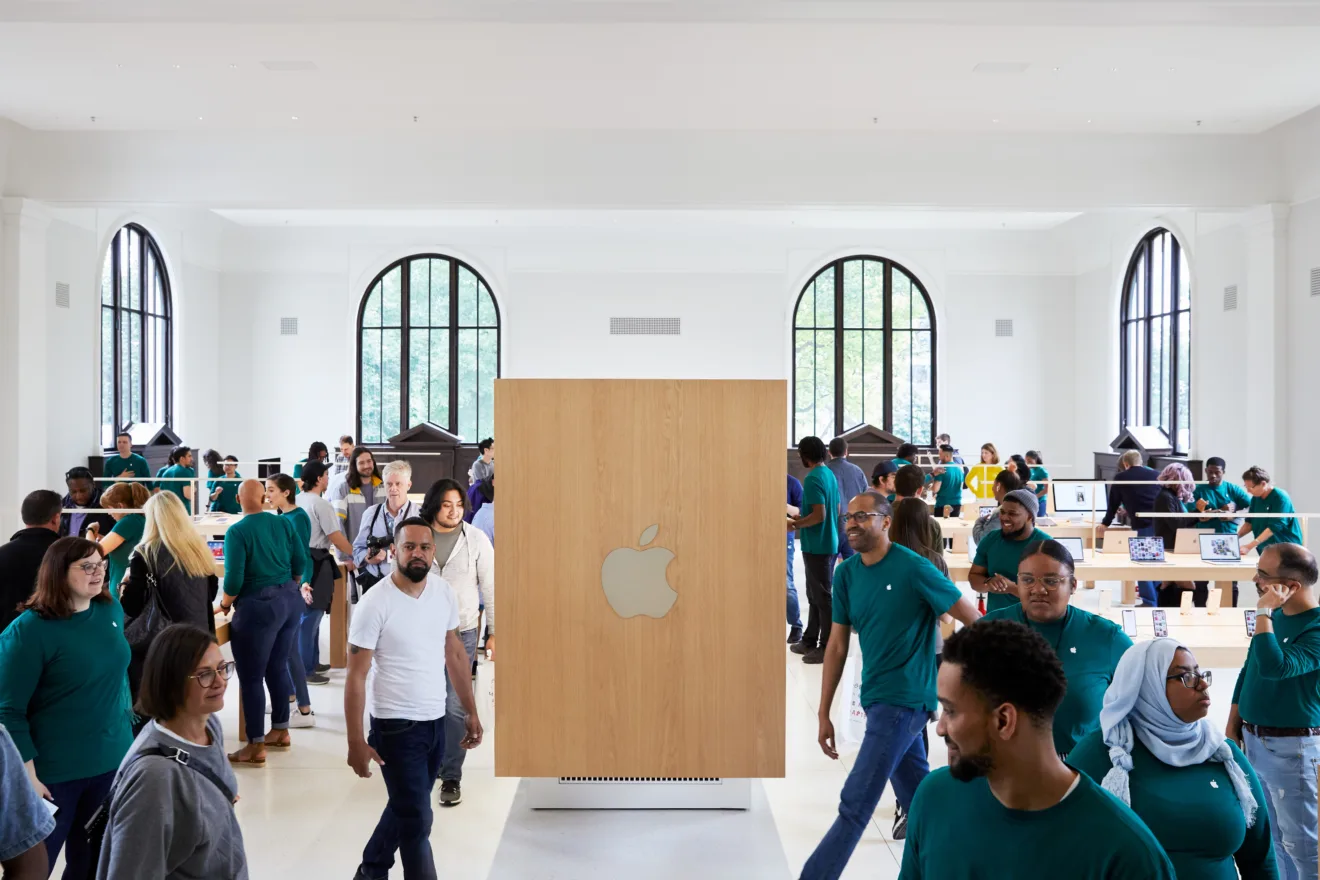 Instalação minimalista traz o logotipo da apple em uma sala branca e está cercada de pessoas