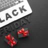 Imagem mostra as palavras "Black Friday" perto de um laço de presente e algumas caixas