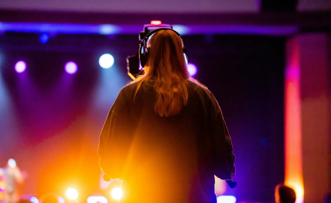 Mulher de costas manipulando uma camera em um evento