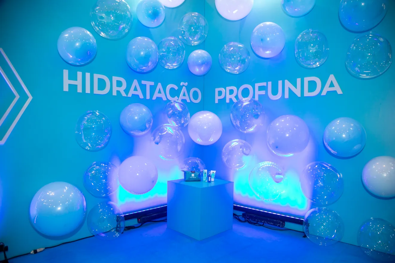 Foto mostra a ativação de Avon Renew em Salvador, que traz um ambiente azul, com balões que simbolizam espuma, e a frase "hidratação profunda"