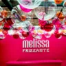 Foto mostra balcão do espaço de Melissa Frizzante na cor rosa. Balões transparentes e coloridos estão presos ao teto.