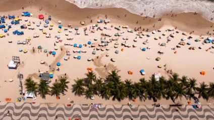 Imagem aérea da praia de Copacabana em um dia tranquilo mostra a calçada típica da orla de Copacabana, barracas e o mar