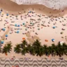 Imagem aérea da praia de Copacabana em um dia tranquilo mostra a calçada típica da orla de Copacabana, barracas e o mar