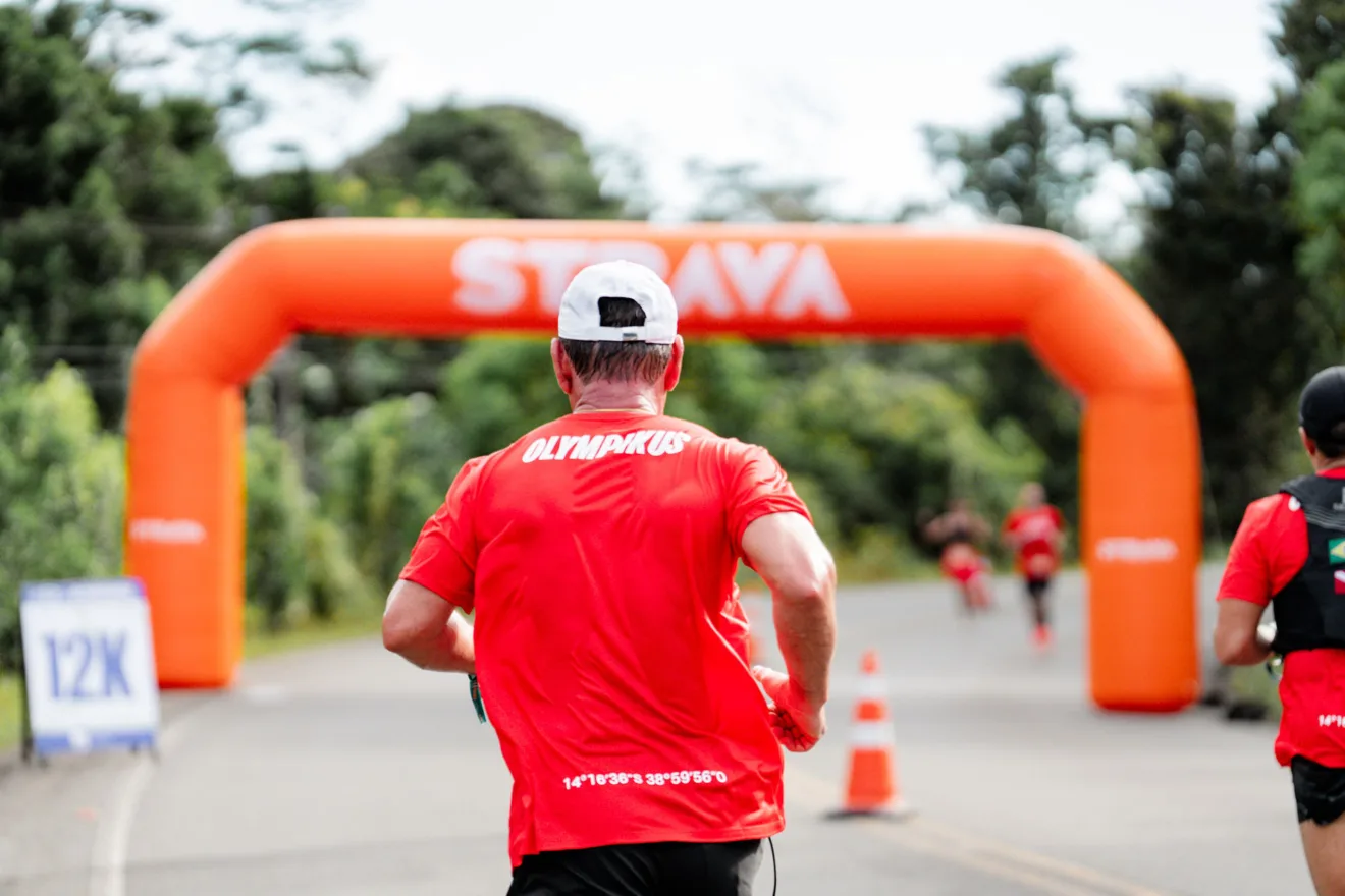 Imagem mostra um corredor indo em direção a um totem do Strava, portando uma camiseta da Olympikus