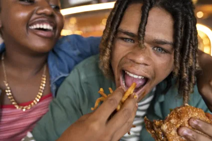 Imagem de um homem negro comendo um hamburguer com batatas fritas, simbolizando McDonald's e diversidade