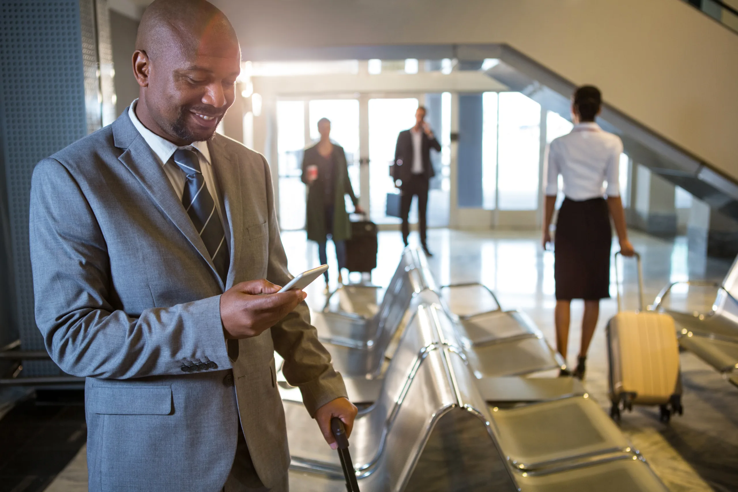 Imagem de um homem olhando o celular na sala de espera de um aeroporto, simbolizando o setor de viagens corporativas