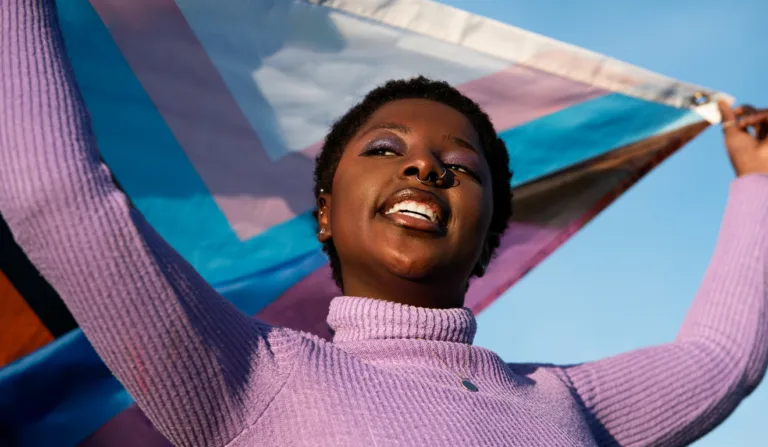Imagem de uma mulher negra segurando uma bandeira de apoio ao público LGBTQIAPN+ Imagem de uma mulher negra segurando uma bandeira de apoio ao público LGBTQIAPN+