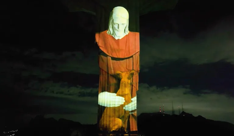 Imagem do Cristo Redentor abraçando um vira lata caramelo em ação da GoldeN