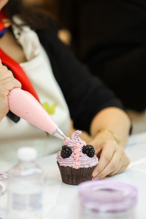 Pessoa confeitando cupcake em evento da Dove