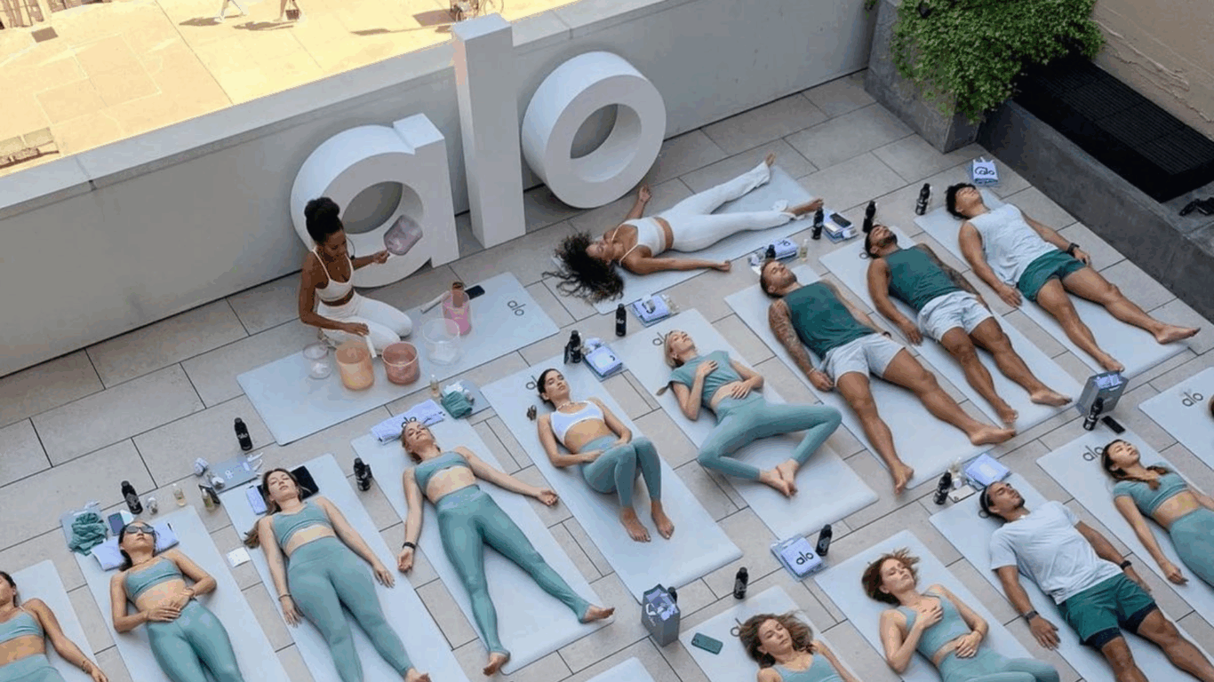 Pessoas praticando yoga em um terraço em um evento de wellness da Alo