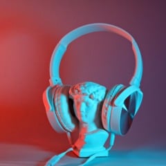 Imagem mostra uma pequena estátua de dorso masculino utilizando headphones
